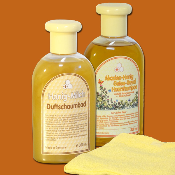 Das „Milch-Bad - 2er“ Geschenkset enthält ein Honig-Milch-Bad und Akazienhonig-Shampoo, verpackt mit einem gelben Waschhandschuh in einer transparenten Badetasche – ideal für die tägliche Hautpflege.