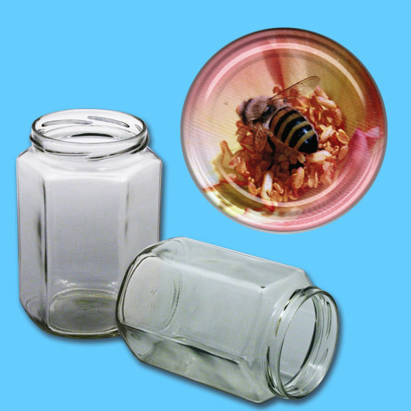 Dieses Honigglas mit einem Fassungsvermögen von 1000 g und einem TO-Deckel, auf dem eine Biene auf einer rosa Blüte abgebildet ist, bietet eine einzigartige Optik für die Präsentation von hochwertigem Honig. Das sechseckige Design sorgt für eine stilvolle und gleichzeitig funktionale Aufbewahrung.